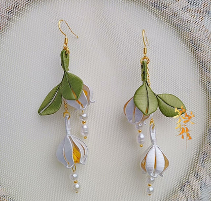 Close-up of a single Chanhua earring highlighting the delicate silk wrapping, luminous freshwater pearls, and secure 925 sterling silver ear hook.