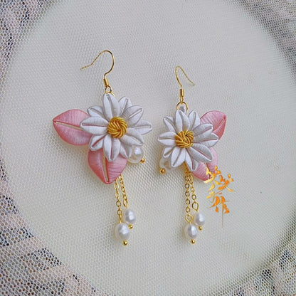 Handcrafted Chanhua flower earrings with white petals, pink leaves, and dangling freshwater pearls on a delicate mesh background.