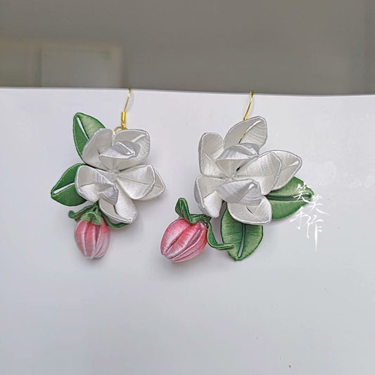 Close-up of the elegant handcrafted white Chanhua flower earrings, highlighting the intricate details of the petals, leaves, and pink buds, showcasing their suitability for daily wear and special occasions.