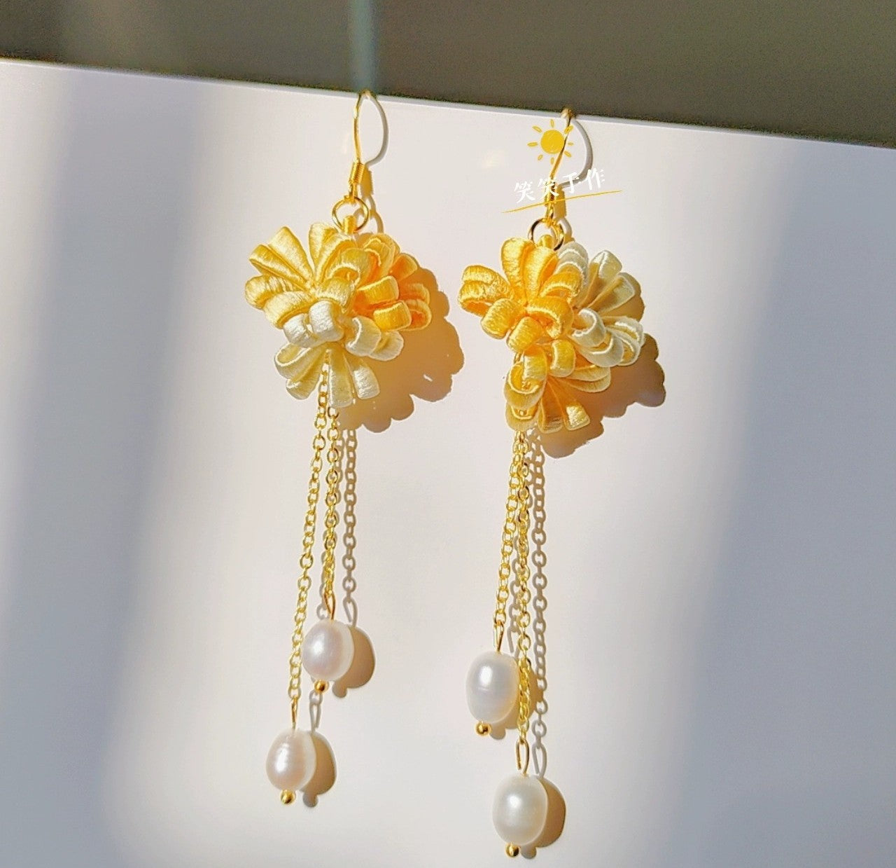 Elegant yellow and white Chanhua flower earrings with natural freshwater pearls on a white background.