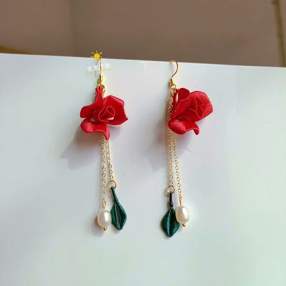 Close-up of handmade Chanhua red rose and green leaf dangle earring with natural freshwater pearl, featuring a 925 silver hook, on a white background.