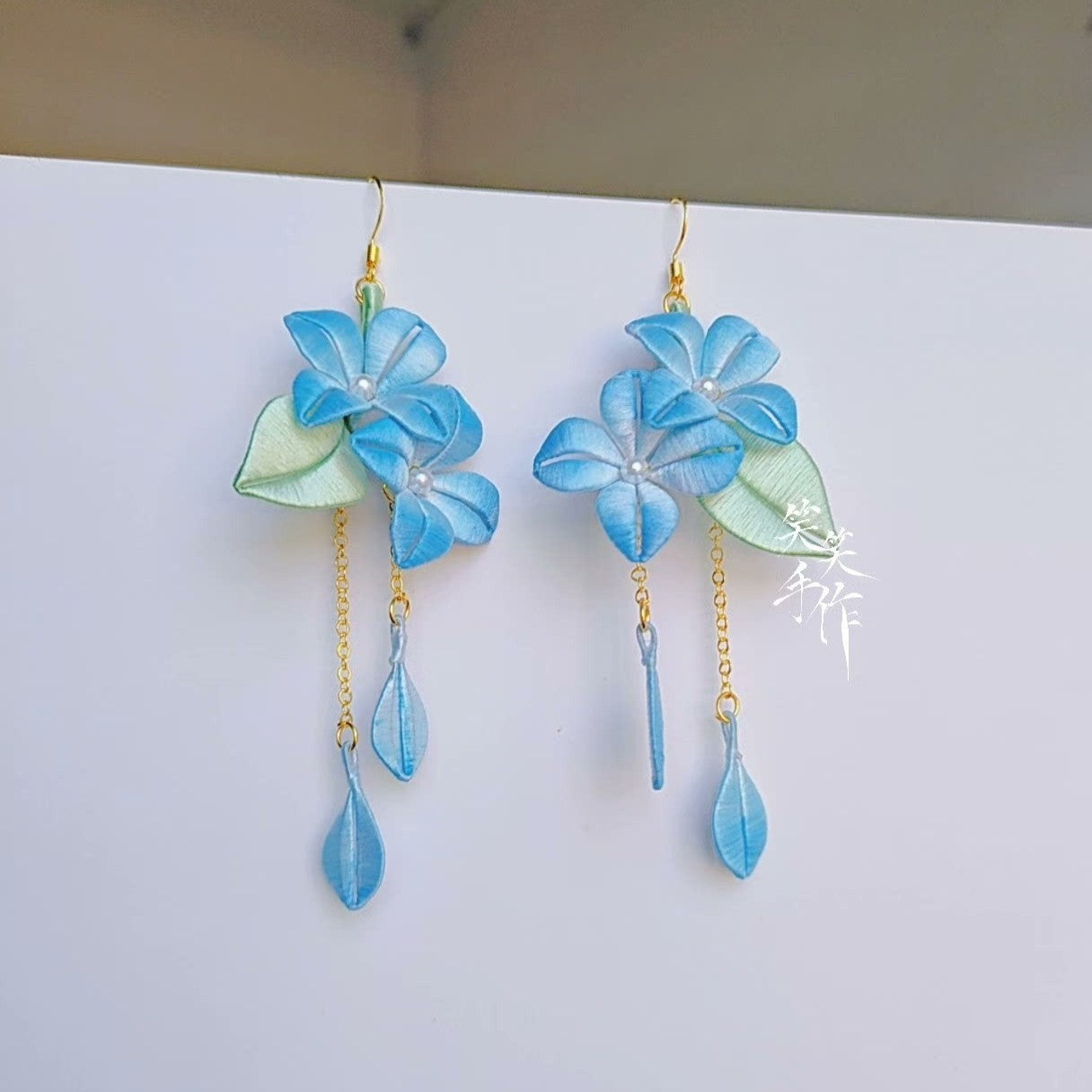 Elegant blue chanhua dangle earrings, handmade with delicate petal drops on gold chains, suitable for formal and casual wear.