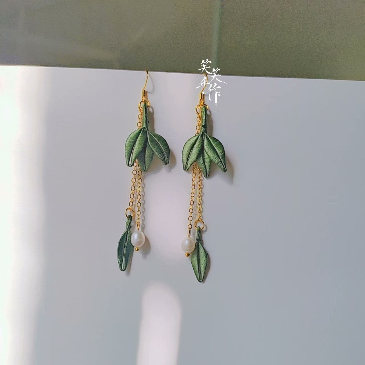 Close-up of a pair of artisan-made Chanhua embroidered leaf earrings featuring elegant freshwater pearls and sterling silver hooks.