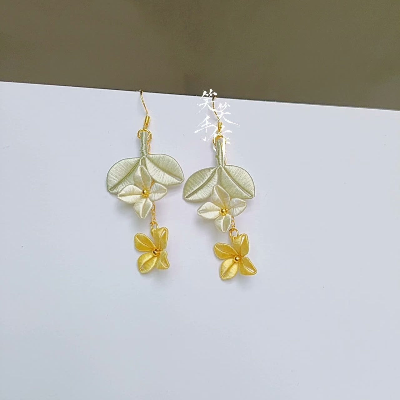 Close-up of a single Chanhua silk embroidered earring, emphasizing the fine texture of the silk, the delicate stitching, and the golden center bead, ideal for everyday and formal wear.