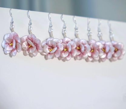 A row of handmade pink camellia flower earrings with 925 sterling silver hooks, hanging neatly against a white background.