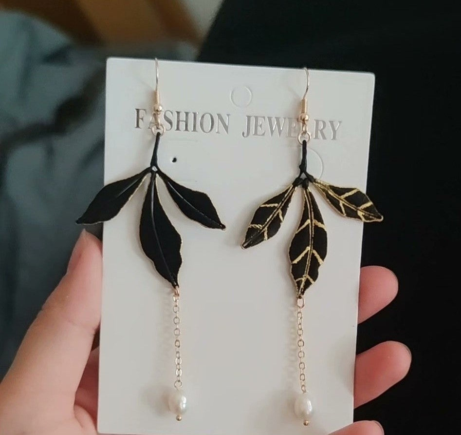 A pair of handmade black Chanhua leaf dangle earrings with gold accents, showing the leaf and freshwater pearl details, displayed on a "Fashion Jewelry" card.