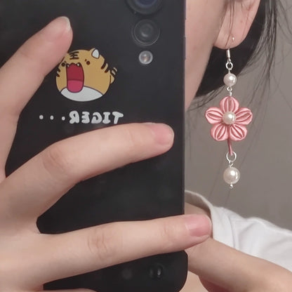 A close-up shot of a person wearing a handmade pink Chanhua flower earring with pearl drops.