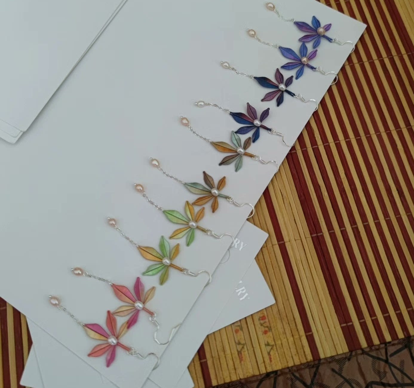 Handmade Chanhua earrings in a rainbow of colors on a white display card.