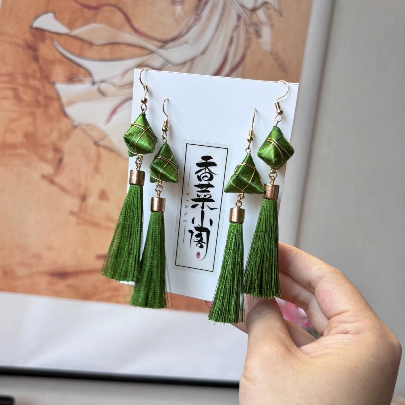 Close-up of a single handmade green tassel earring featuring a Zongzi-like top and a long tassel.