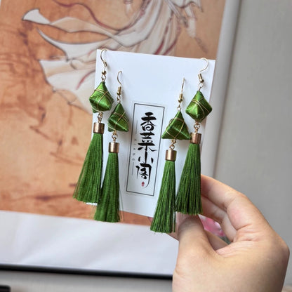 Close-up of a single handmade green tassel earring featuring a Zongzi-like top and a long tassel.