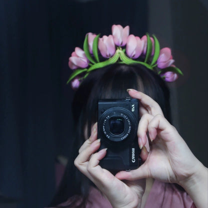 Close-up of a person wearing a handcrafted velvet tulip flower crown, holding a camera, showing the elegant design.