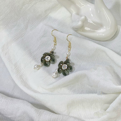 Handmade dark green Chanhua flower drop earrings with a cubic zirconia center and pearl dangles, photographed next to a white ceramic object.