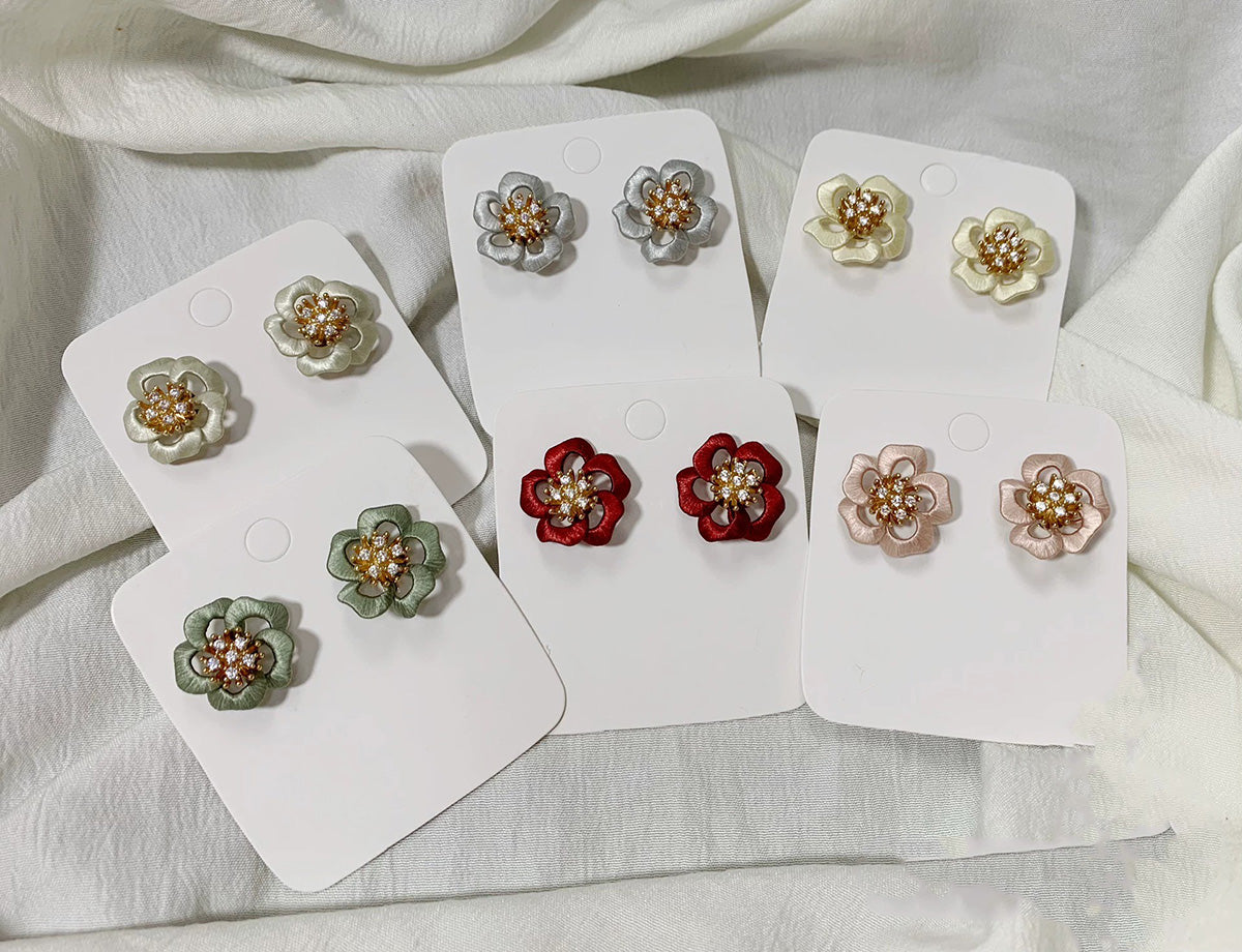 Collection of various colored handcrafted Chanhua floral stud earrings on white display cards.