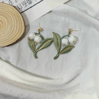 A close-up shot of the handmade lily of the valley earrings with 925 silver hooks on a neutral background, highlighting the detailed craftsmanship.