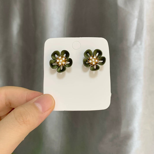 Hand holding a white card featuring a pair of handmade Chanhua green flower earrings with 925 silver hooks.