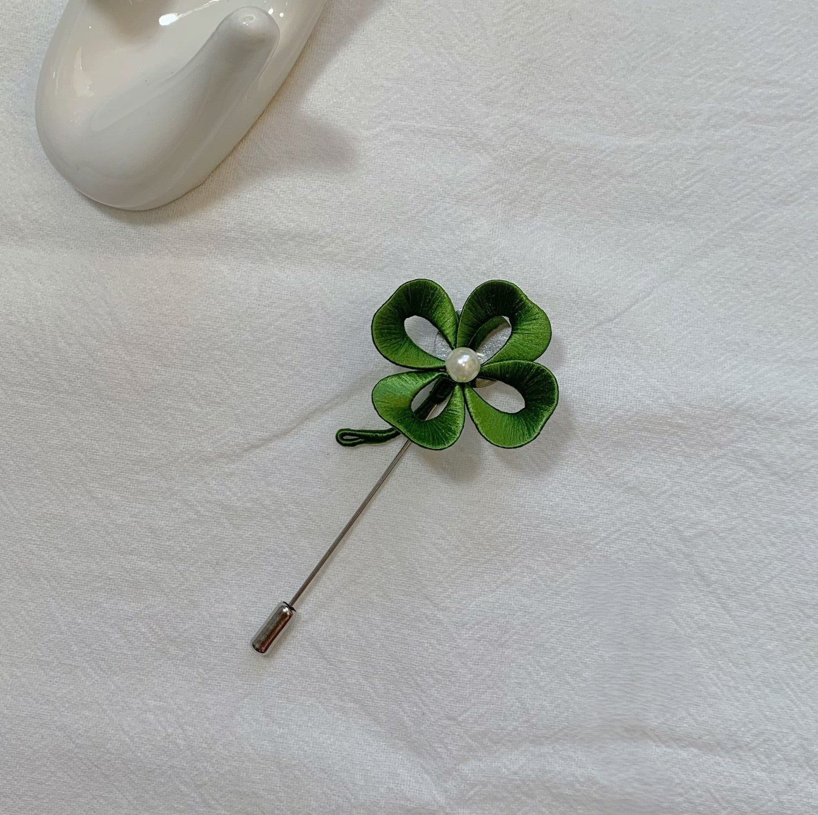 Handmade Chanhua four-leaf clover brooch in green thread with central pearl, elegant clover lapel pin