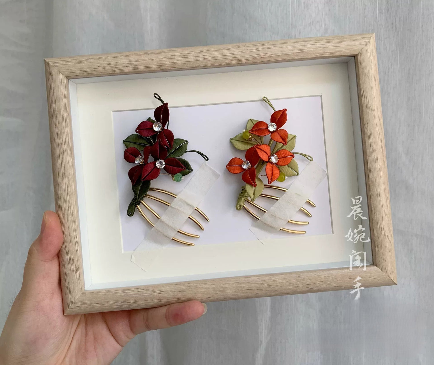 Handmade Chanhua bougainvillea hair comb in red and orange thread flowers with green leaves, pearl accents, and gold comb base, elegant floral hair accessory