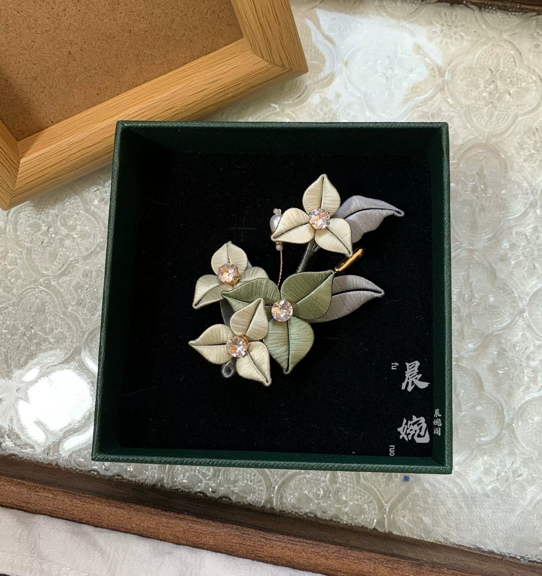 Handmade Chanhua bougainvillea brooch with beige thread petals, crystal centers, and green leaves, elegant floral lapel pin