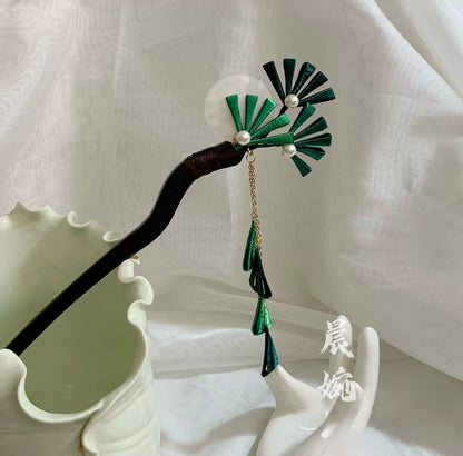 Chanhua handmade green thread-wrapped pine branch hairpin with pearl accents and gold chain tassel, displayed on a dark wooden prop