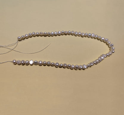 Natural freshwater baroque pearl strand with visible stringing thread for jewelry making.