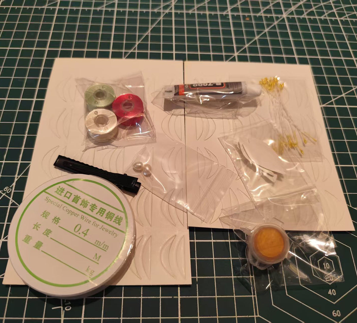 DIY flower craft supply kit containing velvet threads, copper wire, glue, paper templates, and stamens for making a strawberry hairclip.