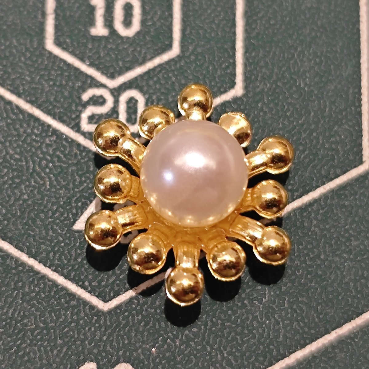 Top view of a single gold flower heart component with a central white pearl.