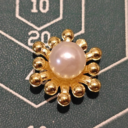 Top view of a single gold flower heart component with a central white pearl.