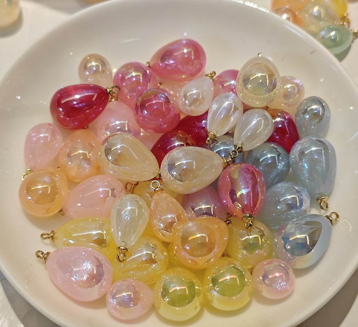 Close-up detail of colorful starry candy teardrop charms with gold bails, showing the sparkling galaxy effect inside the ABS material.