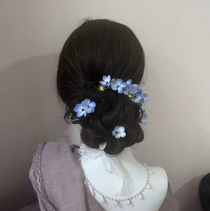 Elegant updo hairstyle adorned with handmade blue mulberry silk Ronghua flowers, showcasing a traditional Chinese hair accessory style.