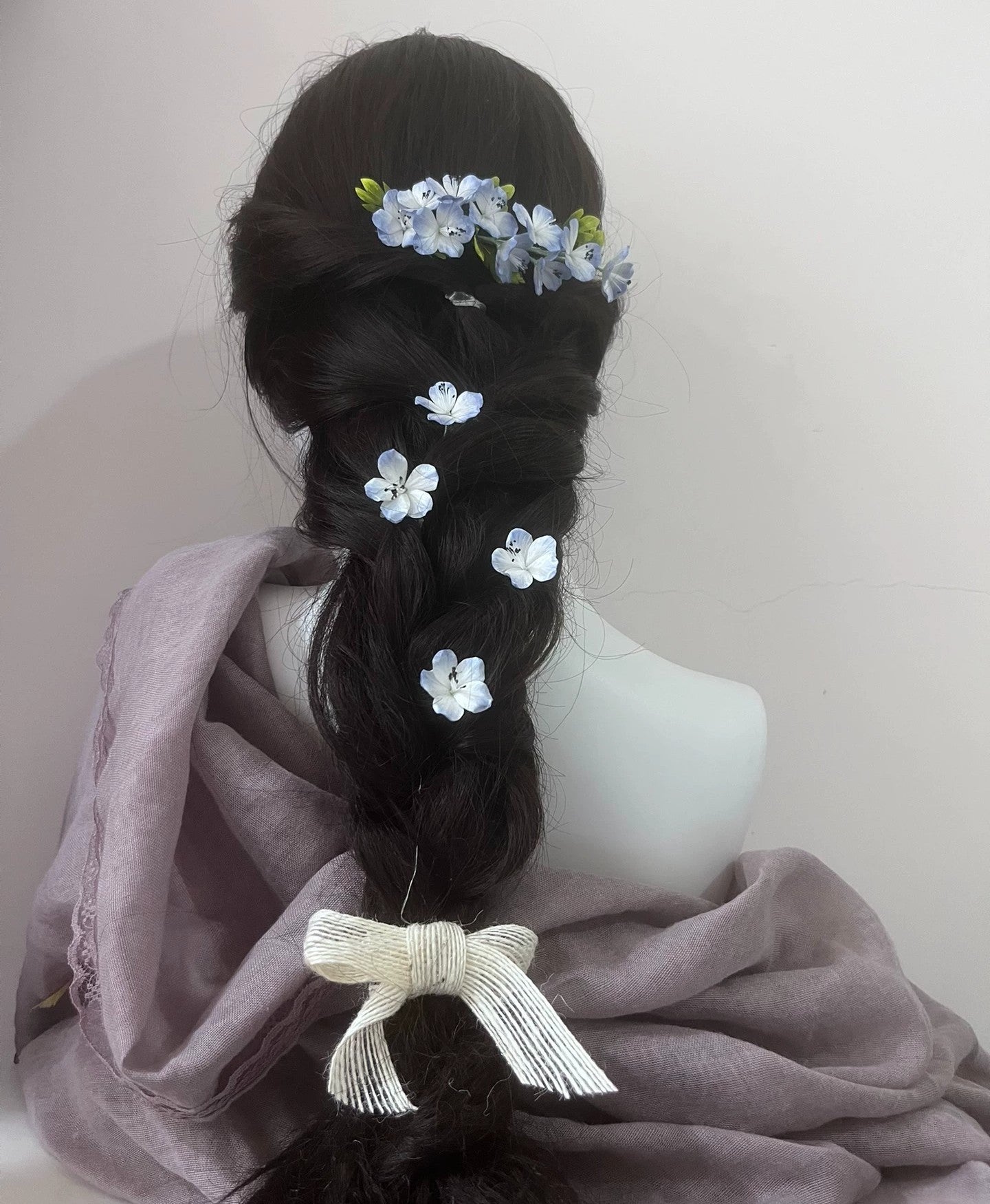 Handcrafted blue and white mulberry silk Ronghua flower pins securing an elegant dark hair bun, showing a formal updo style.