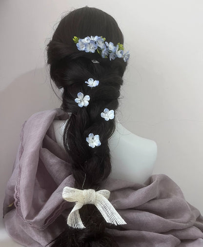 Handcrafted blue and white mulberry silk Ronghua flower pins securing an elegant dark hair bun, showing a formal updo style.