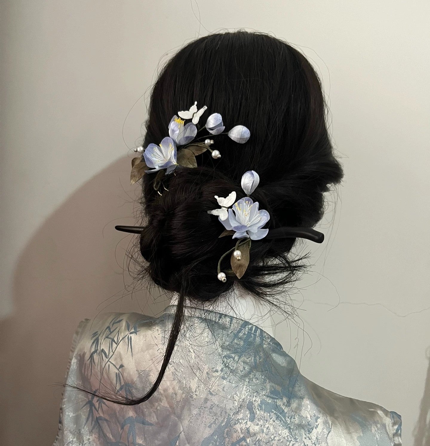 Handcrafted blue mulberry silk Ronghua hair stick and comb set styled in a dark, elegant traditional updo, showcasing the floral design.