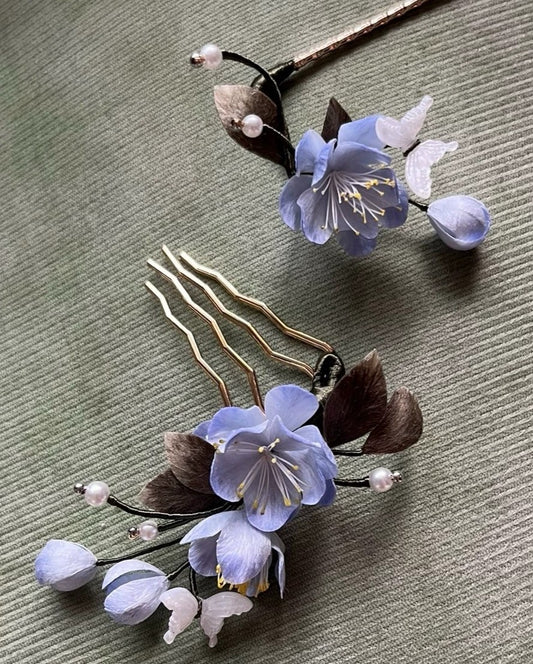 Close-up view of the handmade blue silk Ronghua hair accessory set, featuring a golden comb and a hair stick with pearl and flower accents.