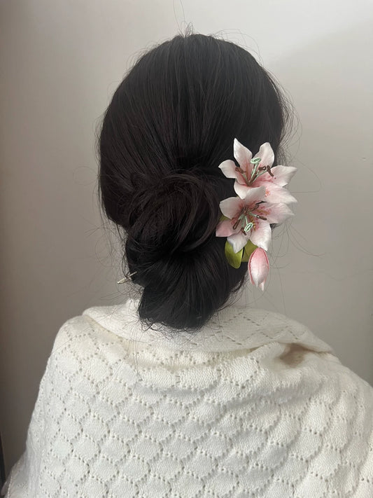 Elegant dark hair bun secured with a handmade pink Mulberry Silk Ronghua Lily hair pin, suitable for a wedding or formal event.
