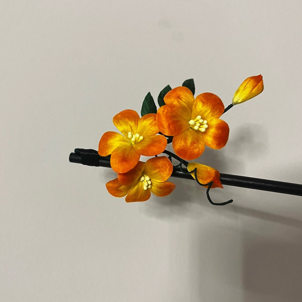 Handmade orange silk Ronghua Trumpet Creeper flower hair stick with a dark pin, displaying the flower cluster and unopened bud.