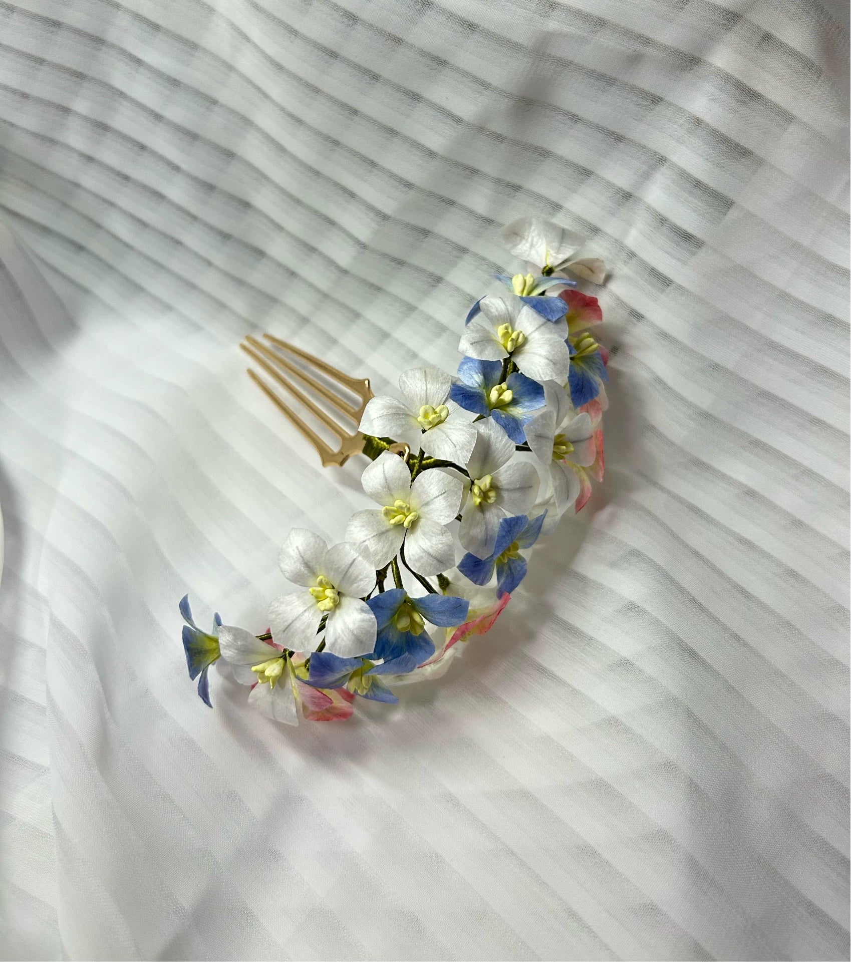 Close-up of the handcrafted mulberry silk Ronghua hair comb, detailing the individual white, blue, and pink flowers.