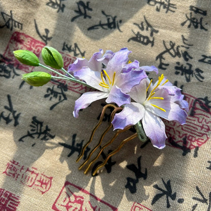 Close-up of handmade Bauhinia flower Ronghua hairpin made from natural purple and white mulberry silk thread on a calligraphy print fabric.