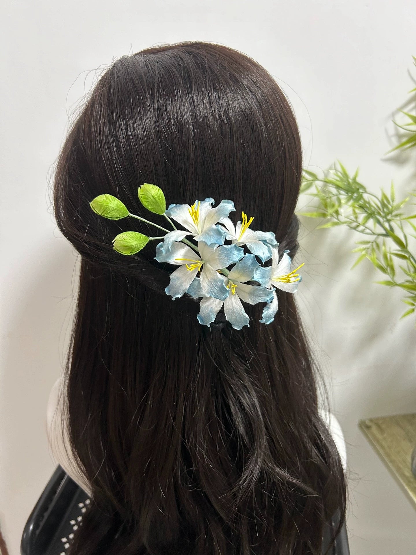 Handmade blue and white Ronghua bauhinia flower hair comb worn in dark brown hair, back view