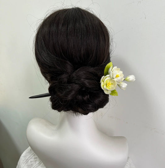 Rear view of white silk jasmine flower hair accessory on mannequin bun hairstyle.