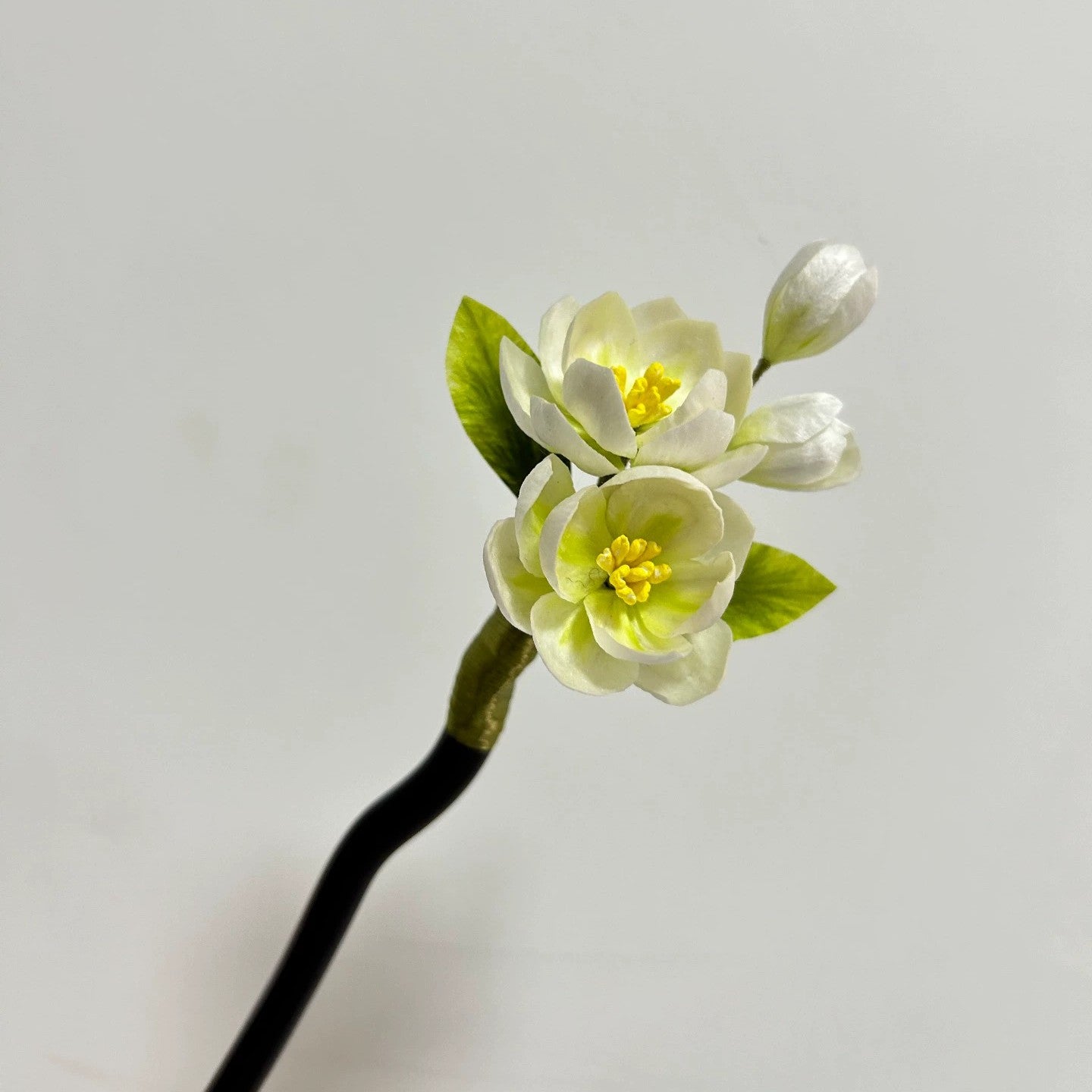 Close-up of handmade white jasmine flower hair stick in natural silk thread.