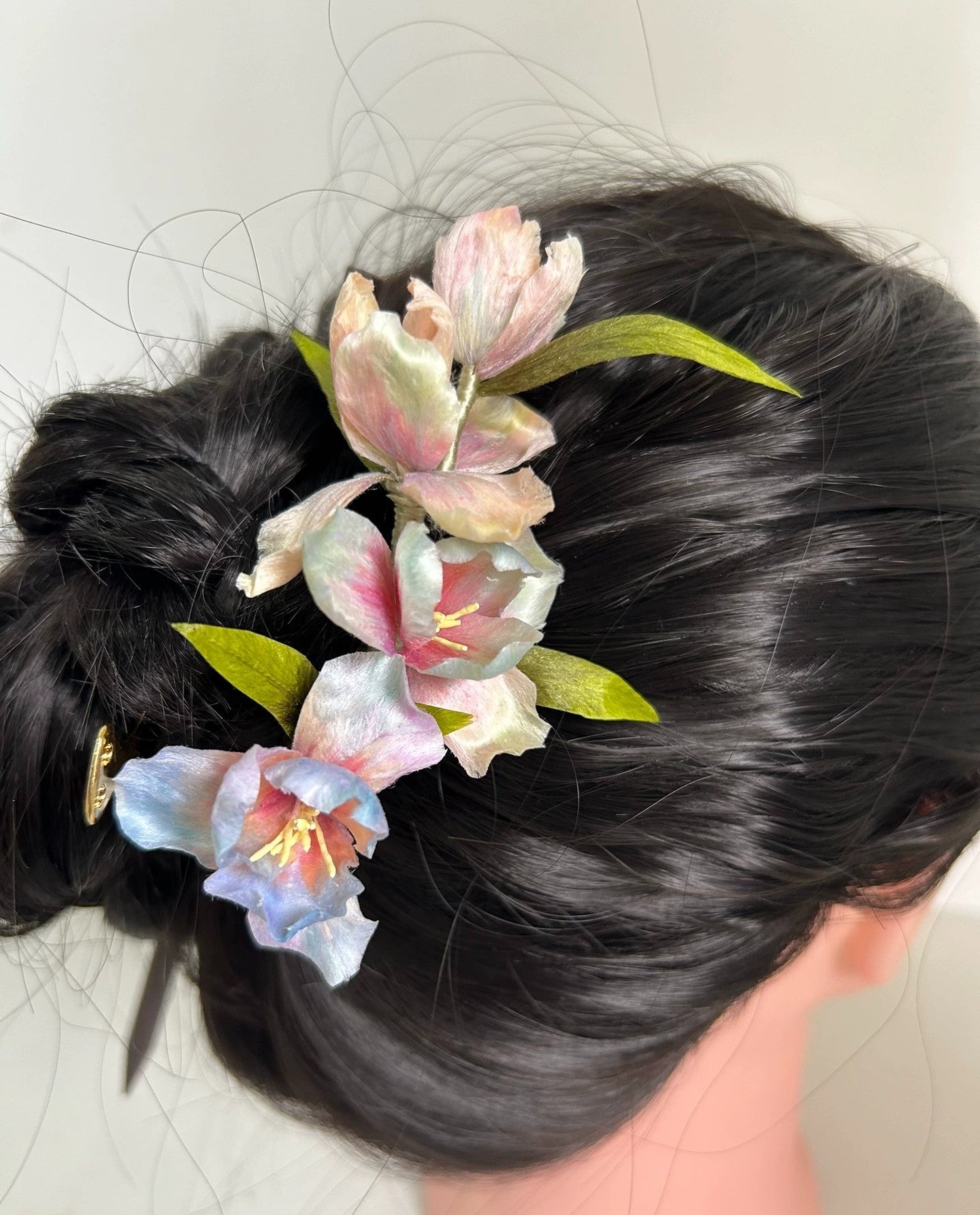 Rear view of gradient color silk iris flower hair comb in bun hairstyle on mannequin.