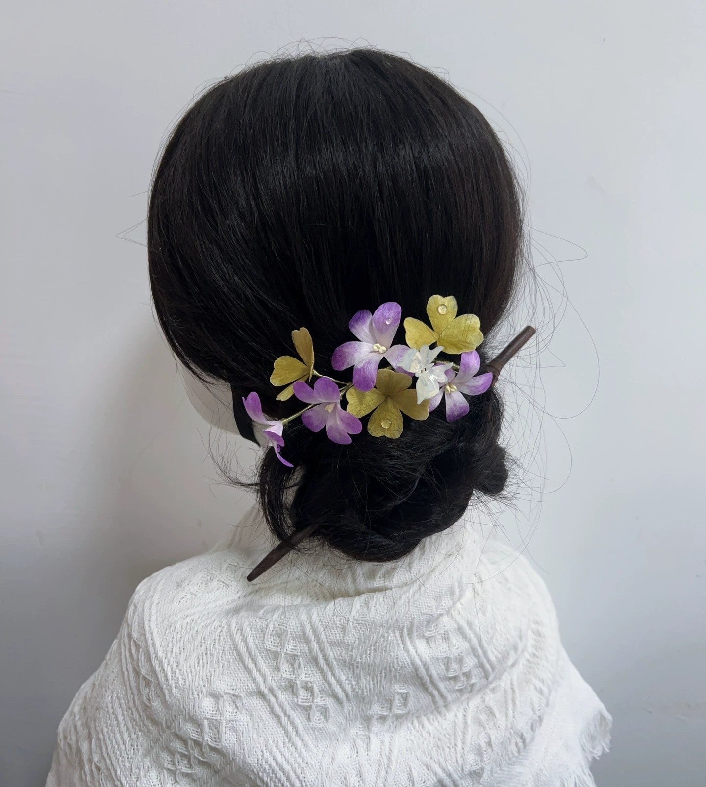 Rear view of silk four-leaf clover hair comb in bun hairstyle on mannequin.