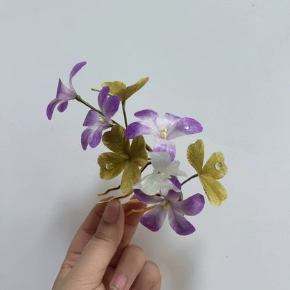 Close-up of handmade four-leaf clover hair comb in natural silk thread held in hand.