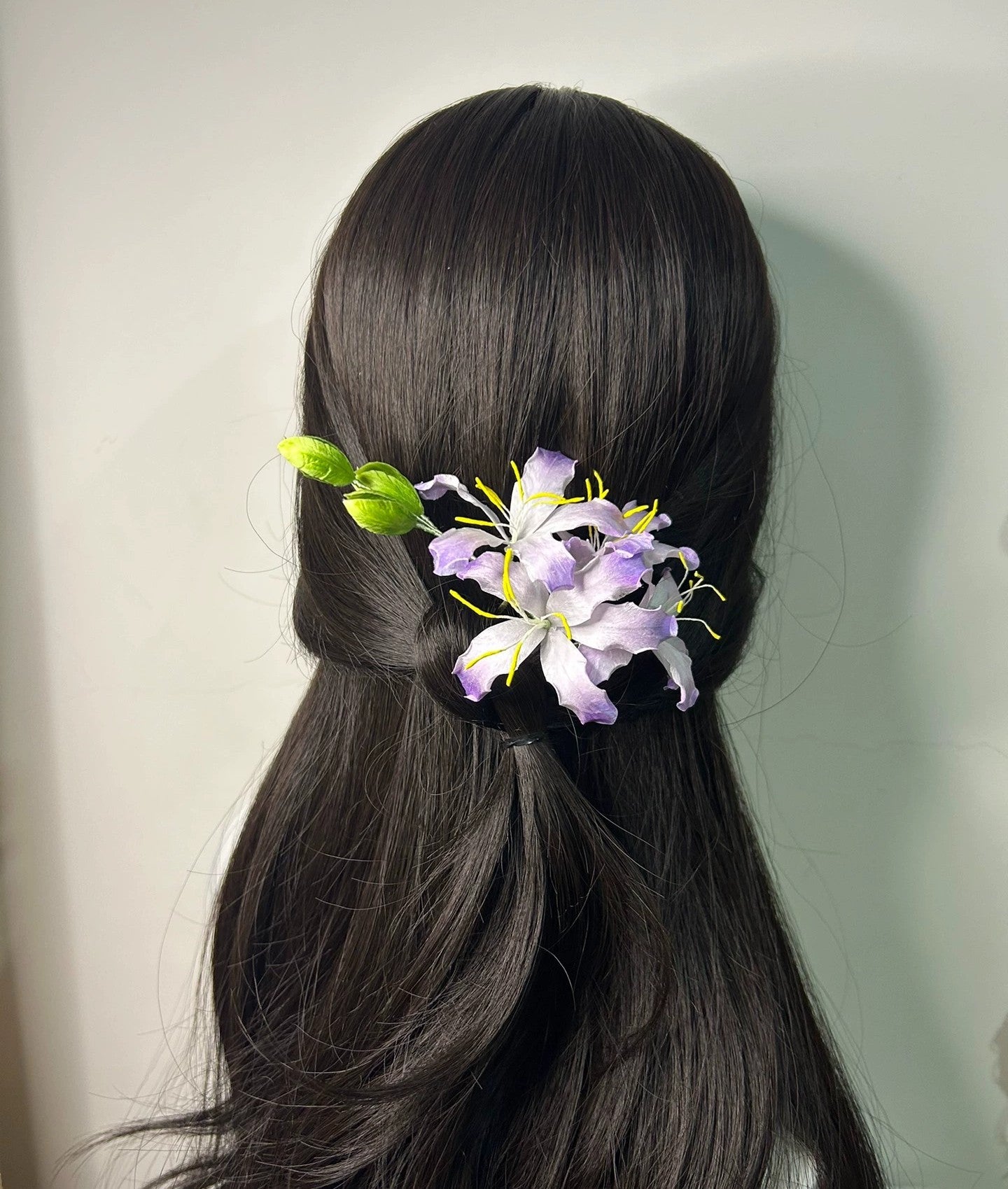 Rear view of purple silk bauhinia flower hair comb in ponytail hairstyle on mannequin.
