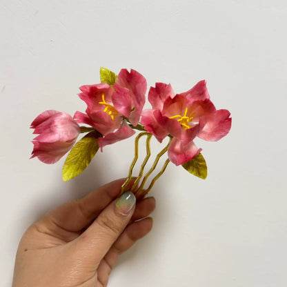 Handmade pink begonia Ronghua velvet flower hair pin held in hand showing delicate silk petals and gold comb