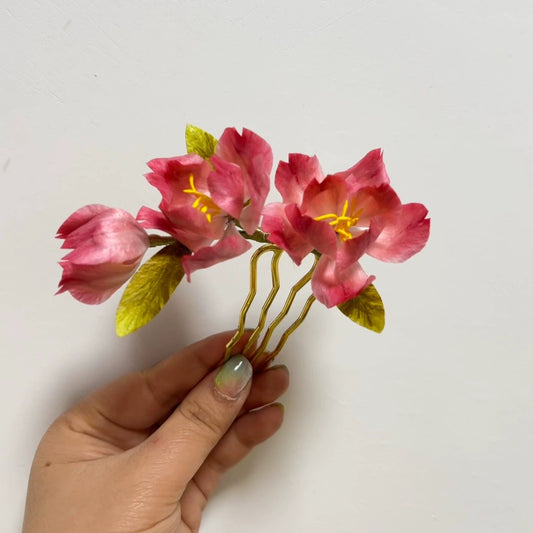 Handmade pink begonia Ronghua velvet flower hair pin held in hand showing delicate silk petals and gold comb