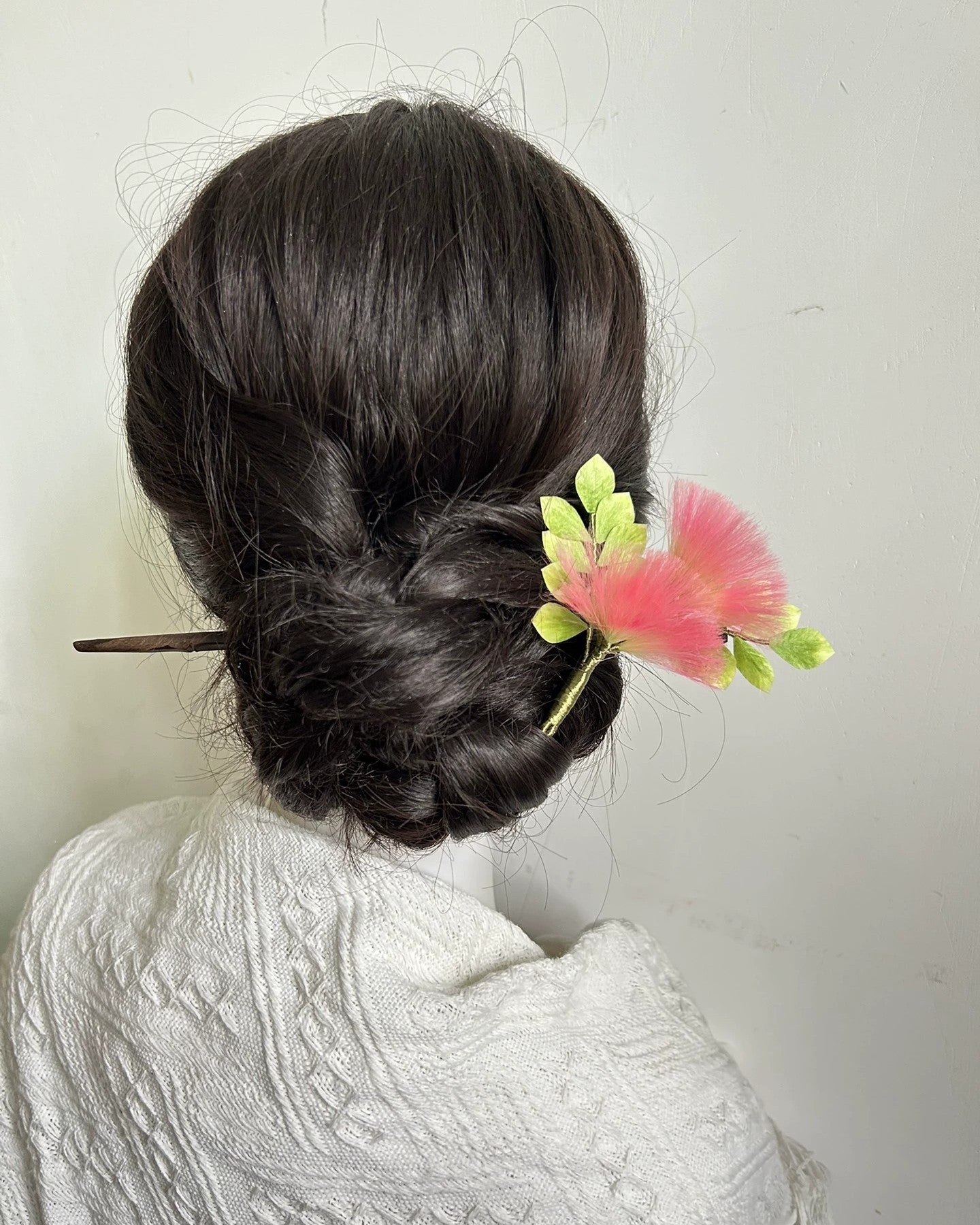 Pink handmade Ronghua Albizia flower hair pin worn in elegant low chignon on dark hair