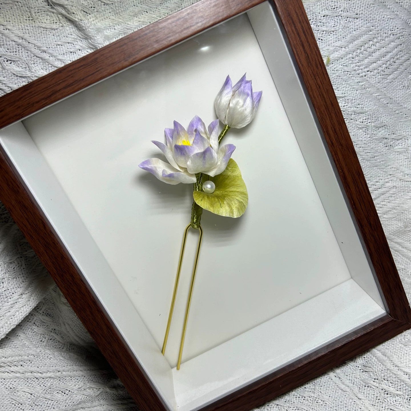 Close-up of velvet Ronghua lotus flower hair stick in soft purple-white gradient with natural mulberry silk thread on wooden display