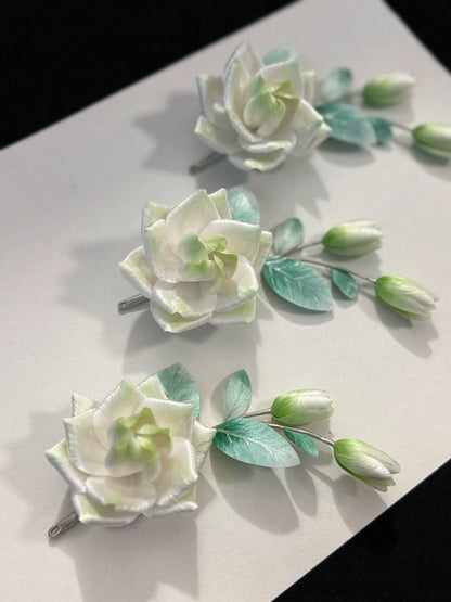 Three handmade mulberry silk Ronghua gardenia brooches displayed together showing natural variation