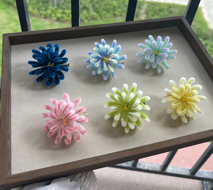 Handmade Ronghua spider chrysanthemum hair clips in navy, blue, mint, yellow, green and pink mulberry silk displayed on wooden tray